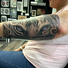 Tiger eyes tattoo on mans left arm