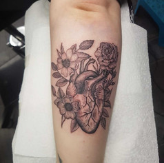 Tattoo of a human heart surrounded by roses