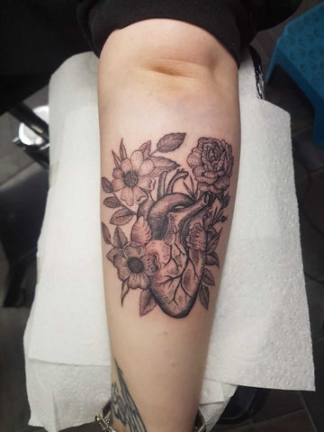 Tattoo of a human heart surrounded by roses