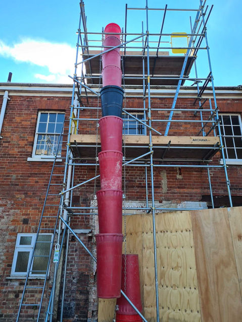 Building with scaffolding and large red tube