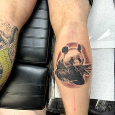 Tattoo of pander eating bamboo on persons right thigh