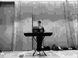 Josh stands behind a keyboard with the score of Made in Dagenham on the stand