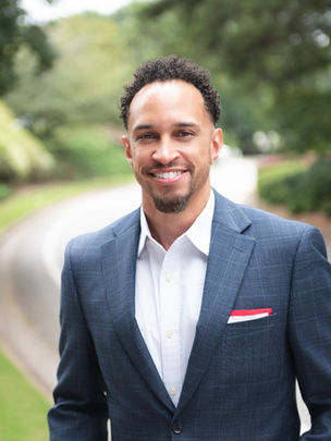 Professional outdoor headshot of a black male engineer captured by Nicole Tyler Photography in a natural setting, showcasing a confident and approachable look for a company website.