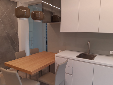 Cucina moderna ristrutturata con mobili bianchi, tavolo in legno e lavello.