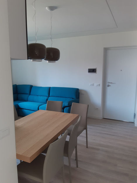 Soggiorno e sala pranzo moderni con divano blu e tavolo in legno.