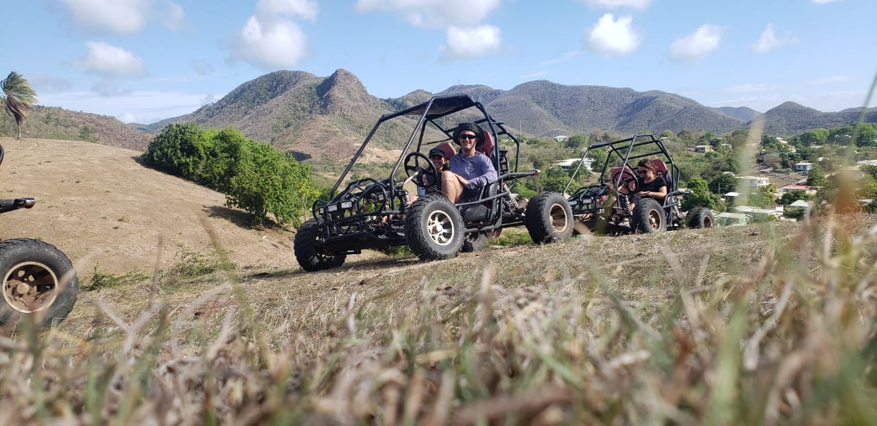 Two open-frame St. Mary's Safari dune buggies exploring a scenic Antigua hillside
