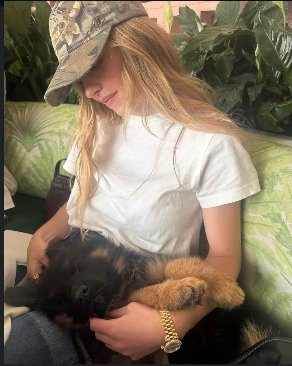 Royal Tribes K9 RTK9 girl in cap cuddling a black and tan long hair German Shepherd puppy on sofa in Fort Collins Colorado