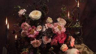 a skull sits on a table surrounded by flowers and candles
