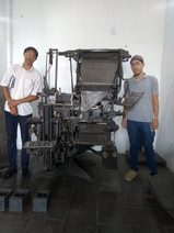 Monarquistas posam para foto, ao lado de maquinário antigo.