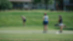 One woman putts while two others watch at a charity golf tournament.