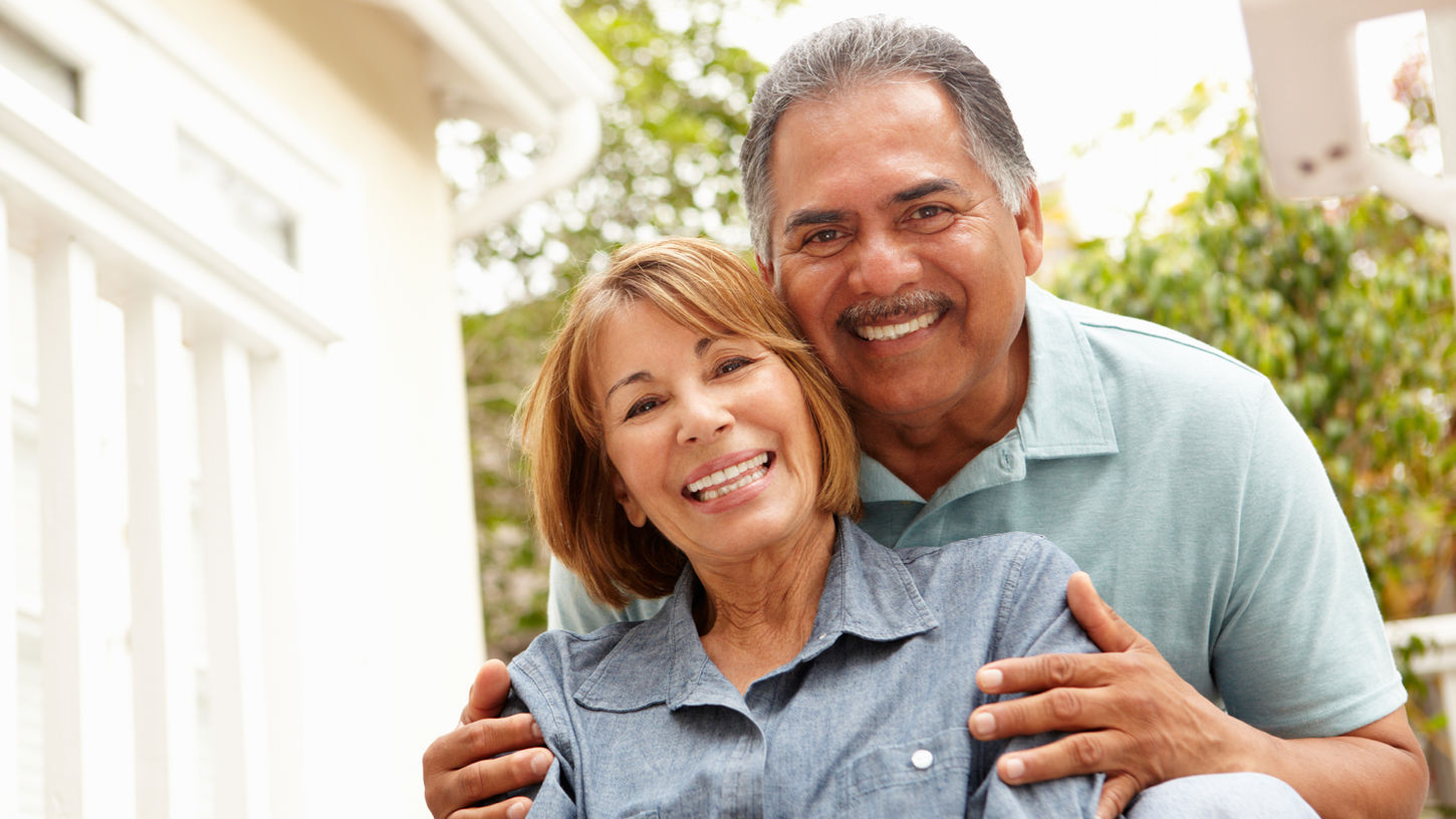 Older latin x couple sitting together smiling