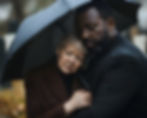 Grieving family comforted under umbrella at funeral, symbolizing support and security offered by final expense insurance 