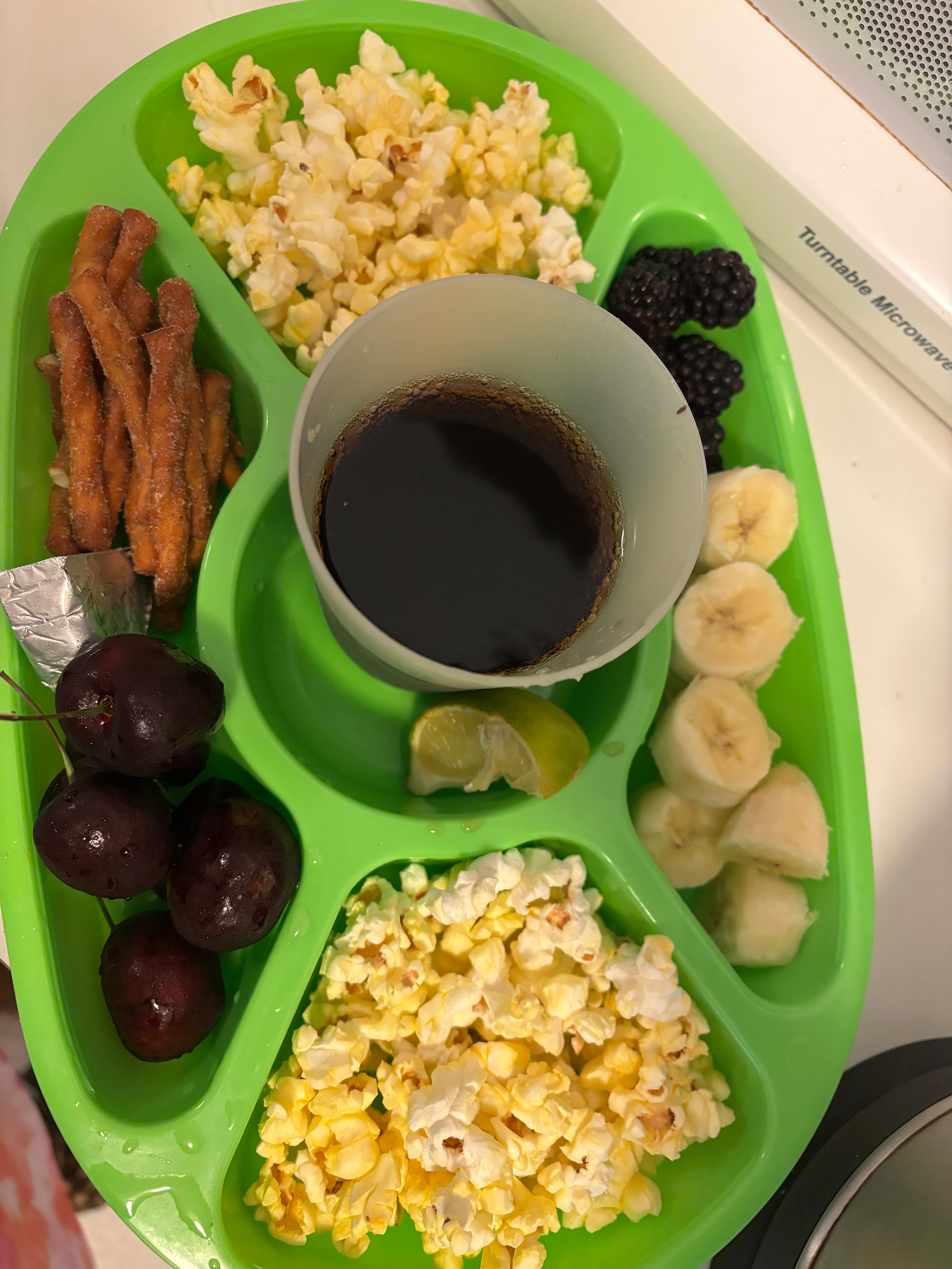 Snack tray with Dr.Pepper, Lime, cherries, blackberries, banana, popcorn, pretzels, laughing cow cheese
