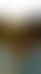 A person relaxes in a outdoor hot tub, looking out at a stunning desert sunset behind rocky mountains.