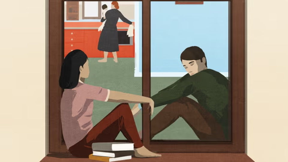 A couple sitting on a window ledge looking into a house where a mum holding her baby is in the kitchen