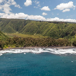 Aerial view of Pololū Valley on the Big Island of Hawaii featuring dramatic emerald cliffs, black sand beach, lush tropical rainforest, rugged coastline, and breathtaking panoramic views along the scenic North Kohala coast.