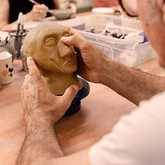 איש מבוגר מפסל דמות מחימר