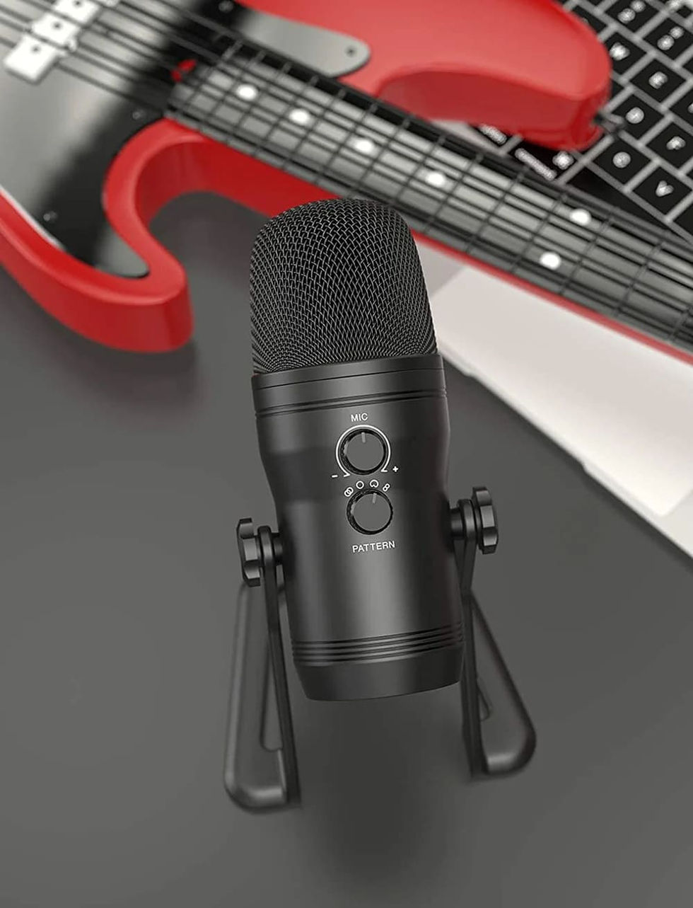 An upright position of a Fifine USB microphone situated beside a red electric guitar.