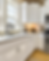 Bright kitchen with white cabinets, stainless steel appliances, granite countertops, and a window. A small lamp and kitchen items are on the counter.