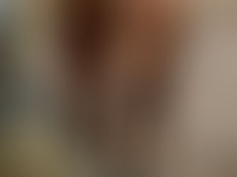 Brown horse with a white stripe eats hay from a black net in a dirt paddock. The horse wears a floral-patterned halter.