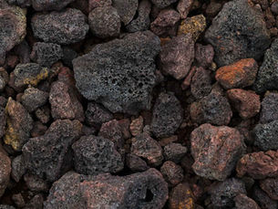 Close-up of variously sized porous volcanic rocks in shades of black, grey, and brown, showcasing rugged textures and earthy tones.