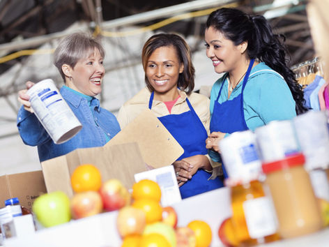 Un groupe de femmes portant des tabliers prépare des paniers alimentaires dans une banque alimentaire.