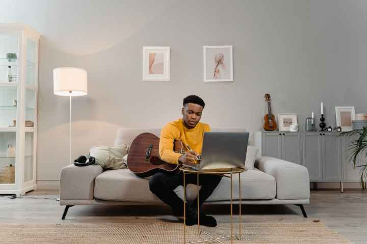 man holding a guitar and writing in the living room