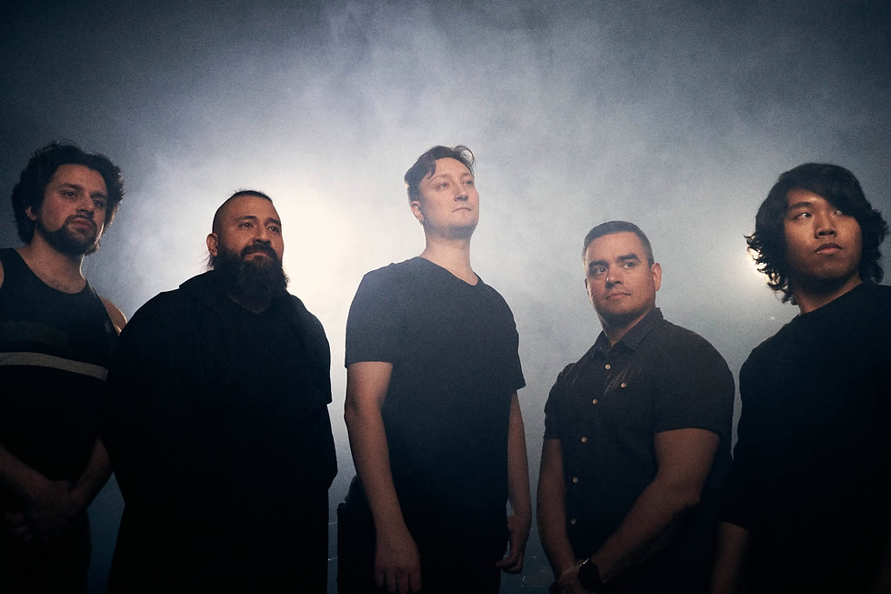 Five men in dark shirts stand in smoky backlight, posing seriously in a moody studio scene. The members of The Divine Project include David T. Anselmo, Eric Divine, Derek "DRock” Boshkov, Ro Stevens, and Mitch Greenham.