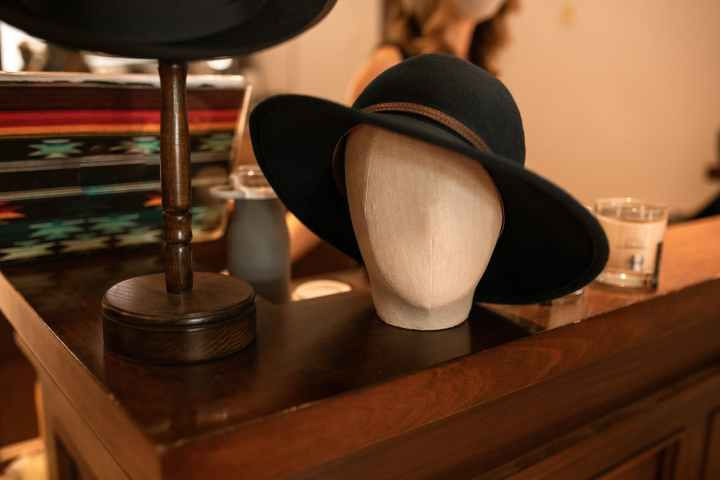 black fedora hat on brown wooden head mannequin