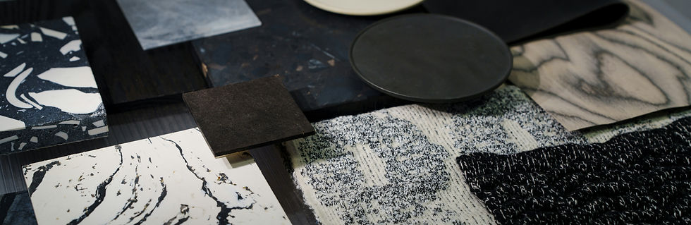Assorted black, white, and marbled material swatches arranged on a table, showing textures and patterns in a design studio