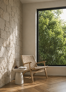 Modern reading nook with stone wall, wood chair, large window, and warm wood flooring