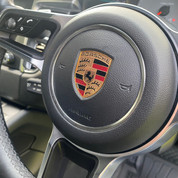 Porsche black leather steering wheel with PORSCHE brand logo.