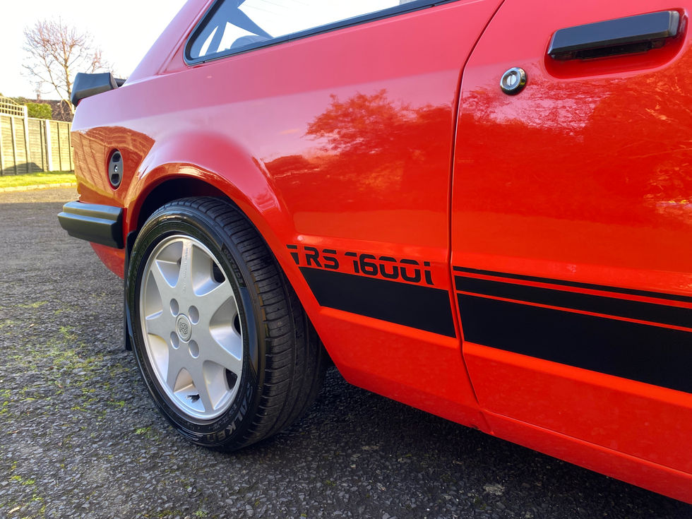 Red classic car side view with 'RS 1600i' text and black stripe.
