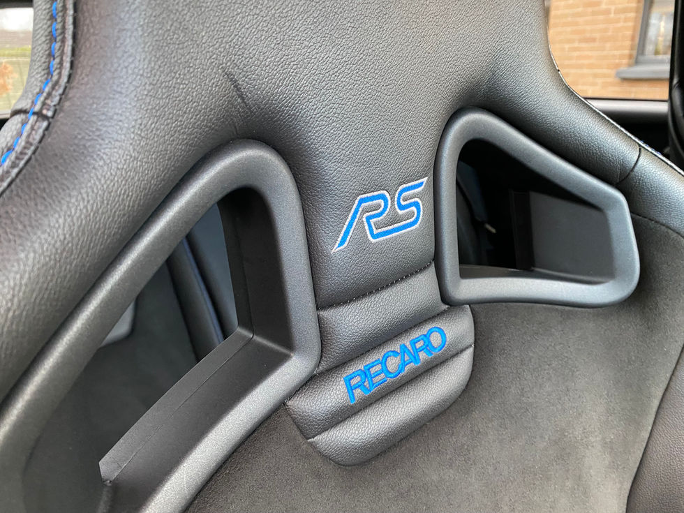 Black Recaro sport seat with blue RS and RECARO logos inside a car.