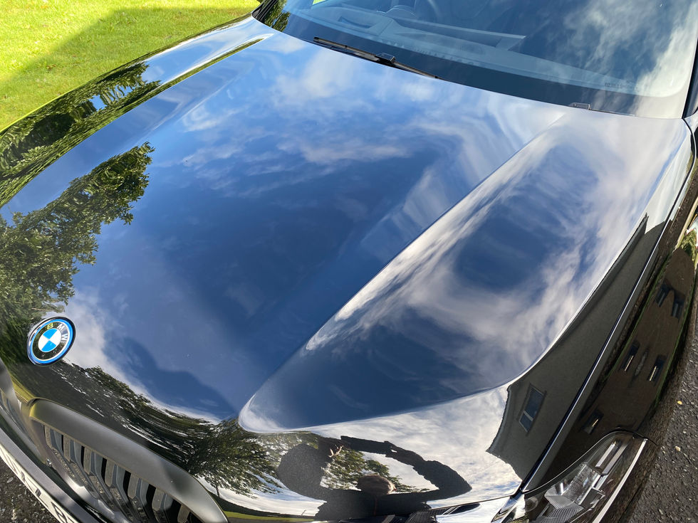 Shiny black BMW car hood reflecting sky and clouds