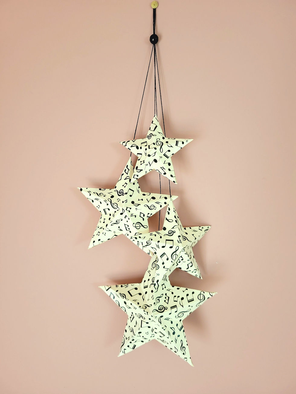Suspension étoiles en papier recyclé avec motifs musicaux noirs, décoration murale artisanale.