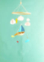 Mobile en papier représentant un voilier suspendu entouré de poissons colorés, de nuages en 3D et d’un petit soleil.