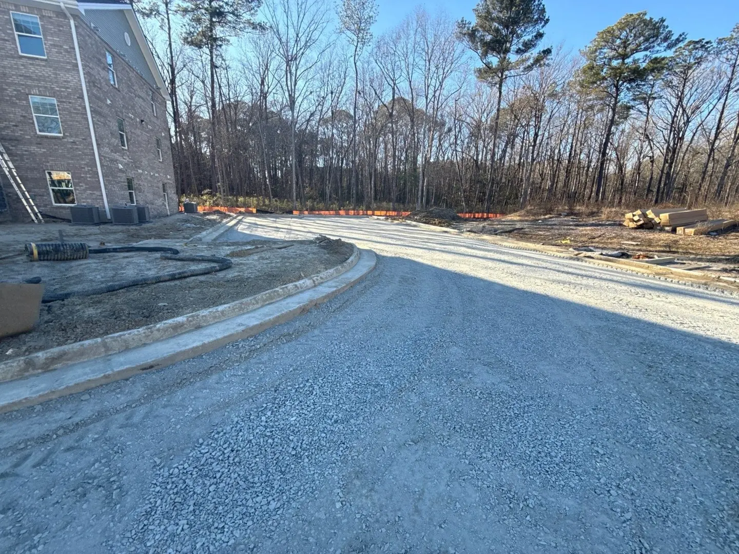 An aggregate access lane curves between new curbs at a multifamily site.