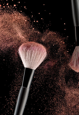 Make-up brush with pink powder explosion on black background.jpg