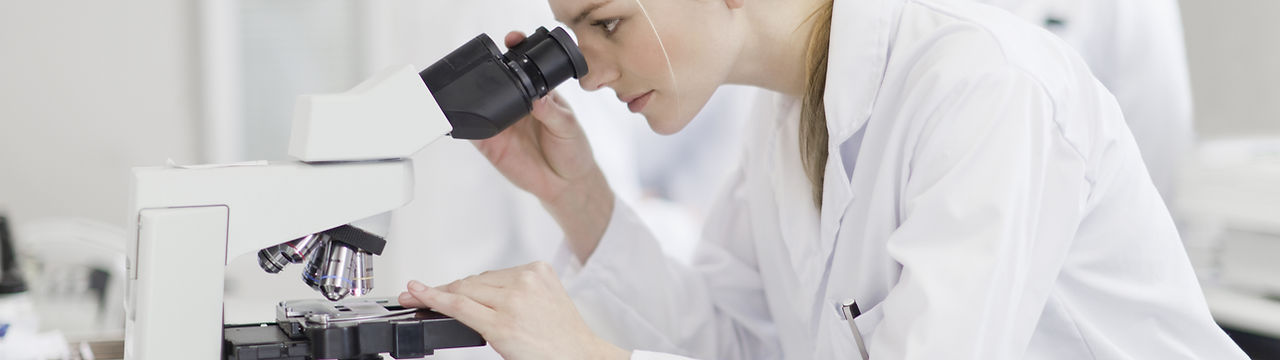 Cientista fêmea que usa o microscópio