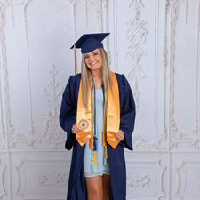 Senior graduate holding diploma while wearing cap and gown