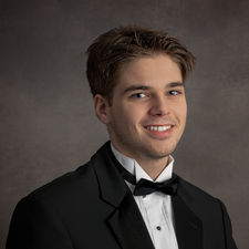 Classic senior portrait of a young man dressed in a black tuxedo