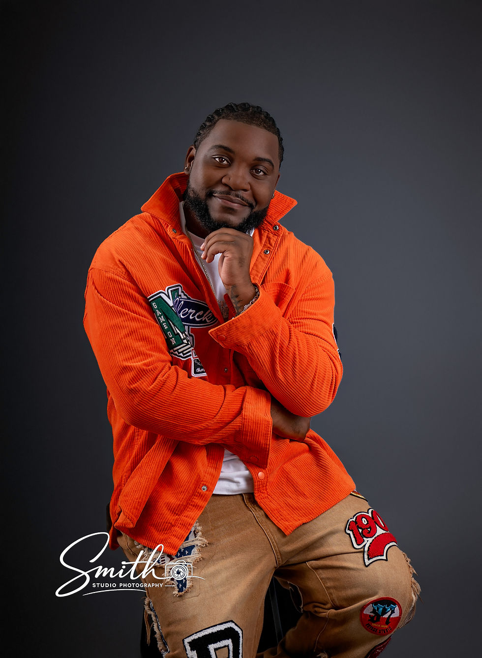 Adult male birthday portrait session with orange jacket and gold chain in photography studio