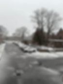 A video of snow falling over a parking lot with centred by dark brick dorms.