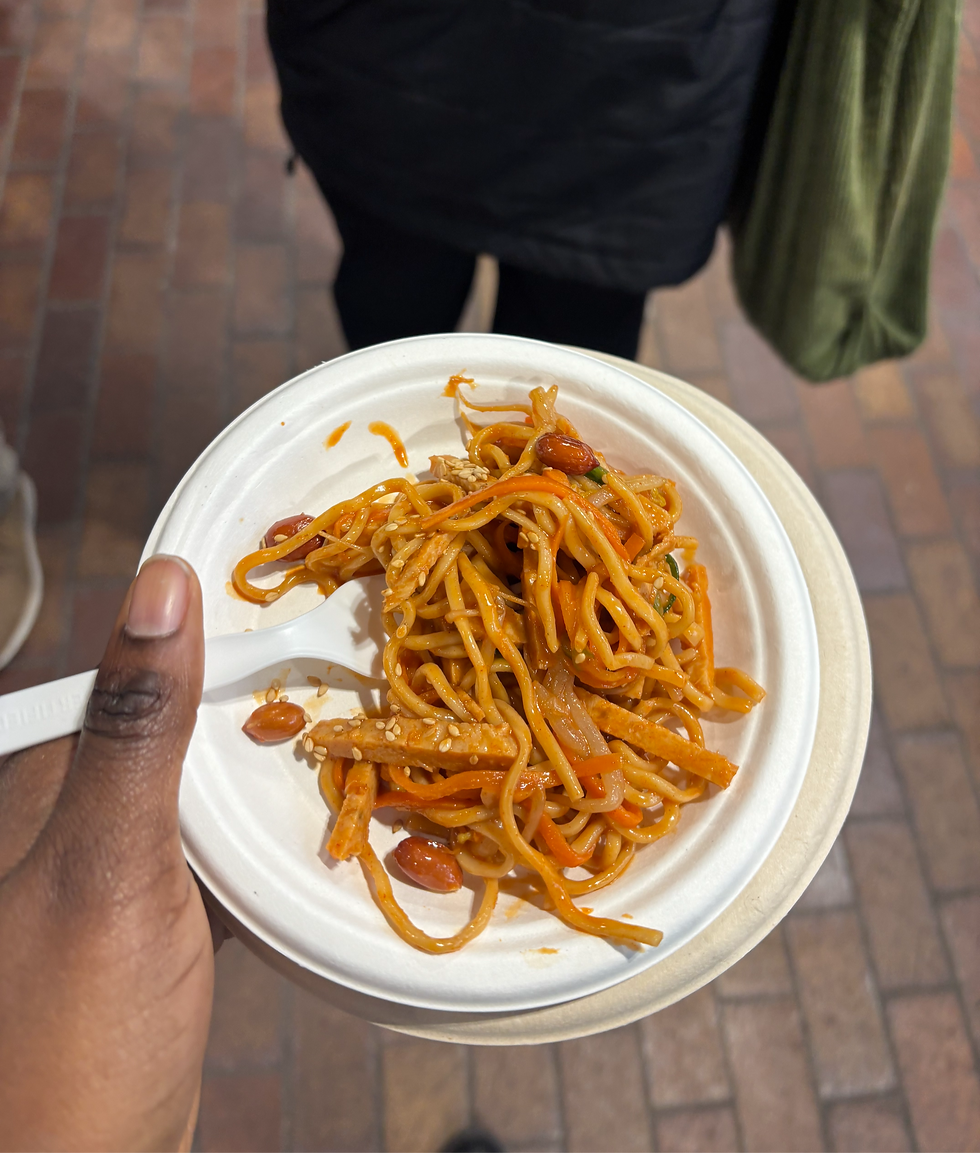 A plate of noodles in spicy red sauce, with beans, carrots, peppers and plant-based chicken substitute.