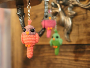 A pink bird in focus with two birds out of focus behind it on a wooden background