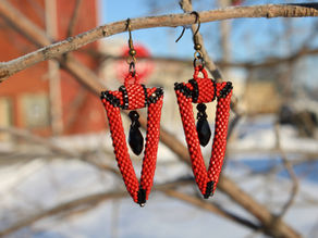 Red and Black inverted triangle earrings hanging from a tree branch.