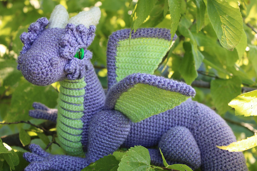 A purple crochet dragon in a tree glaring at the camera