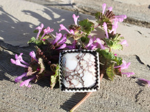 A stone pendant sitting on purple flowers