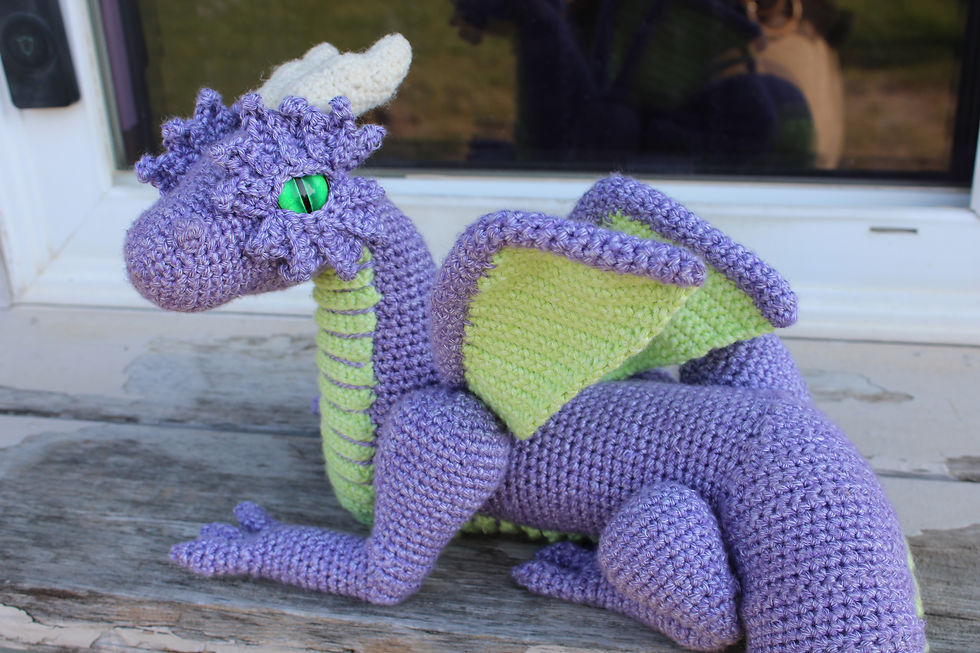 A purple crochet dragon on a wooden railing